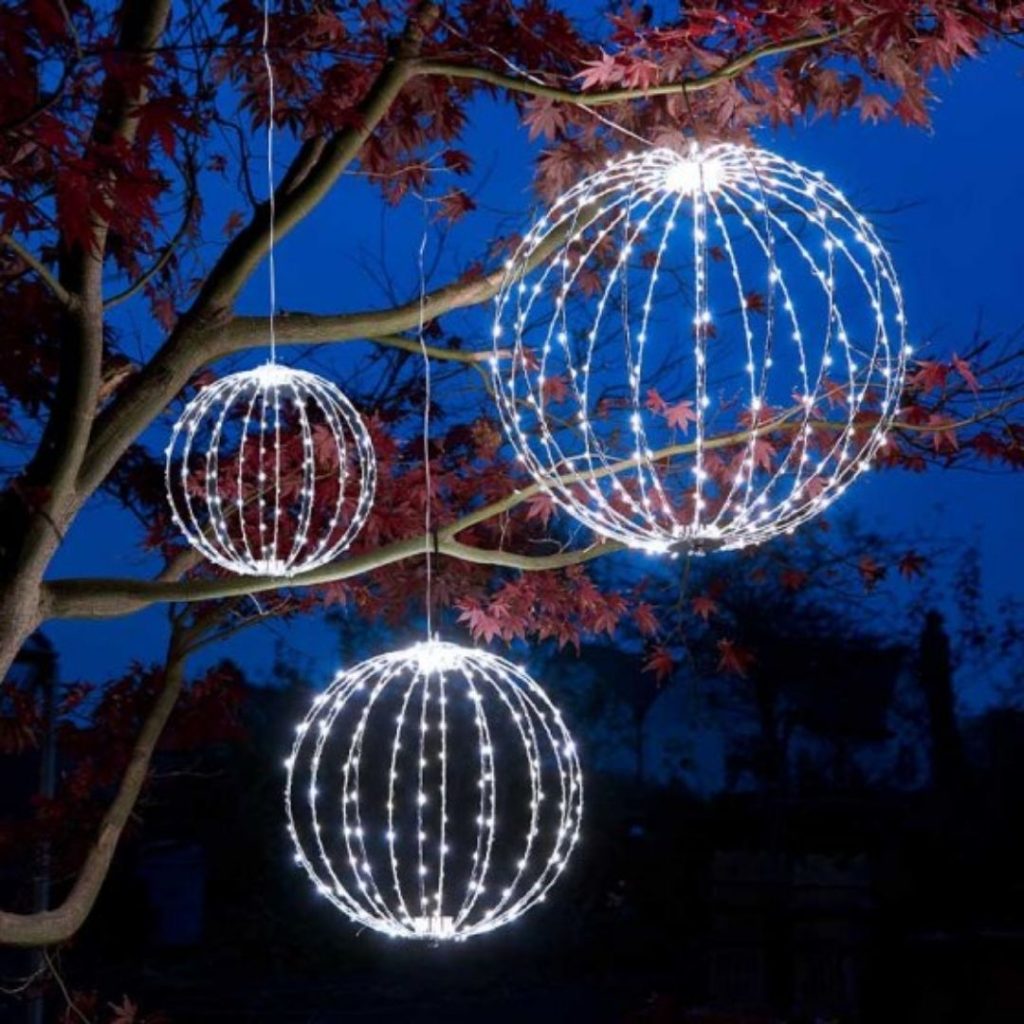 Hanging Three Kings Twinkle Orb Lights glowing in warm white LEDs outdoors at night.